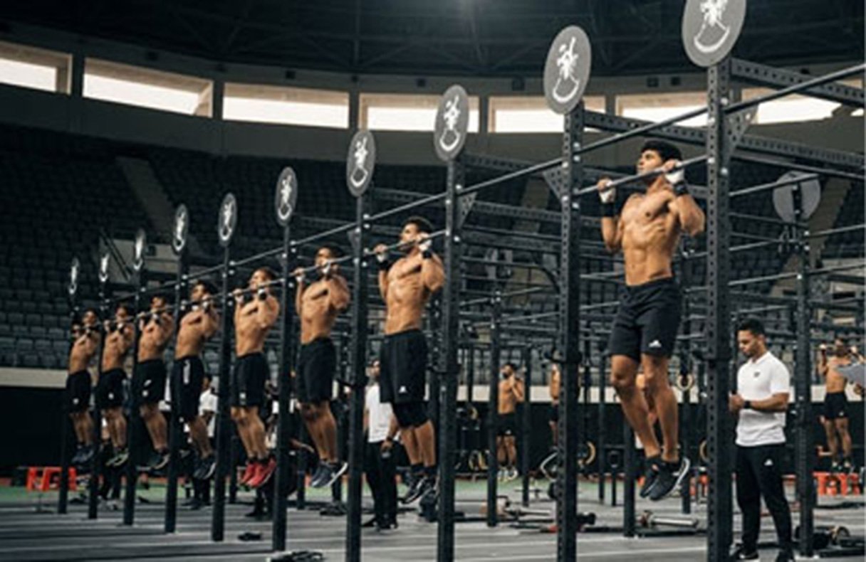 Athletes hanging from pull-up bars in formation